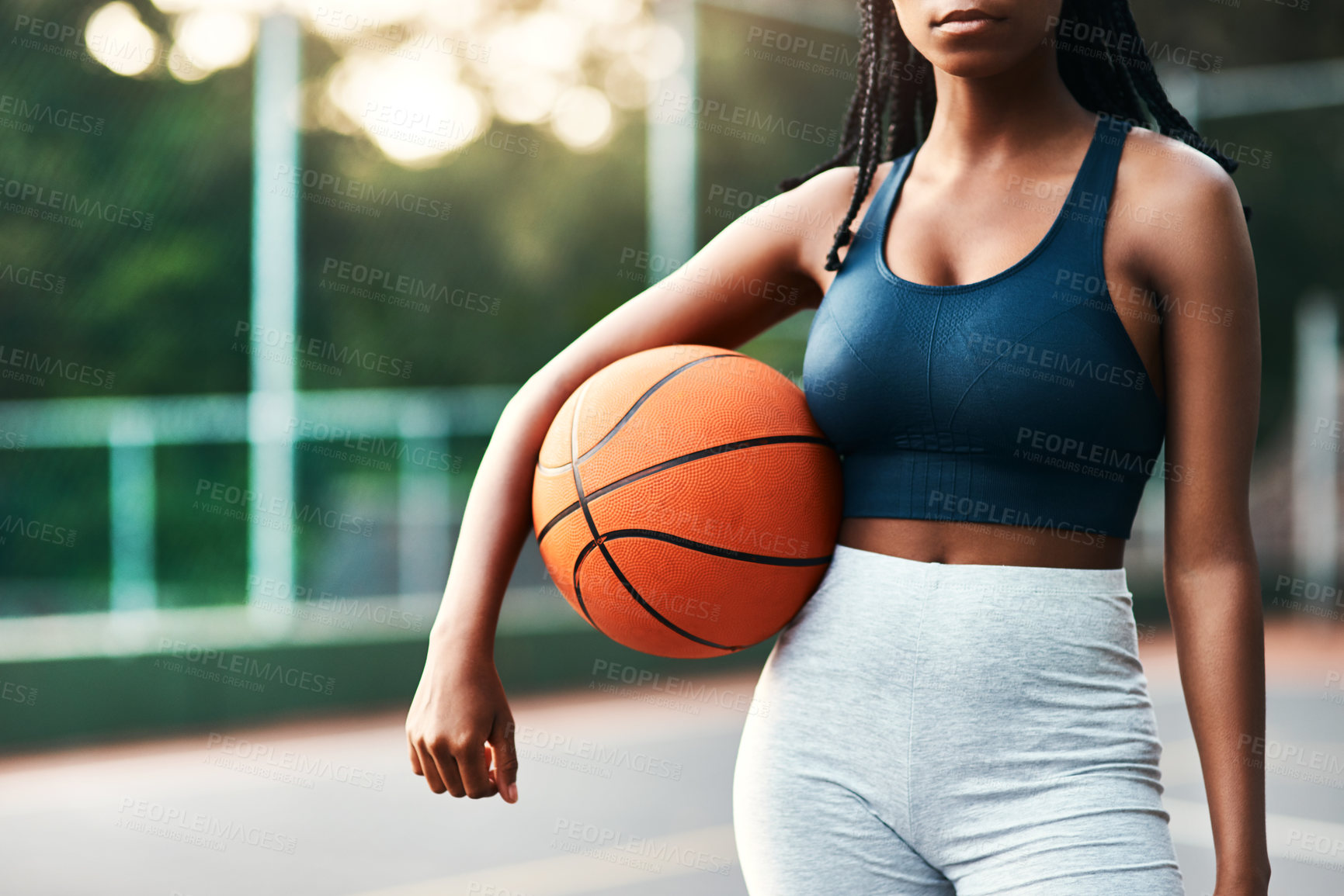 Buy stock photo Cropped shot of an unrecognizable sportswoman standing on the court alone and holding a basketball during the day