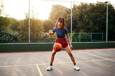Buy stock photo Full length shot of an attractive young sportswoman standing alone on a basketball court and warming up with the ball