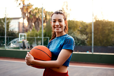 Buy stock photo Cropped shot of an attractive young sportswoman standing on the court alone and holding a basketball during the day