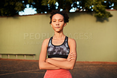 Buy stock photo Cropped shot of an attractive young sportswoman standing alone on the court with her arms folded during the day