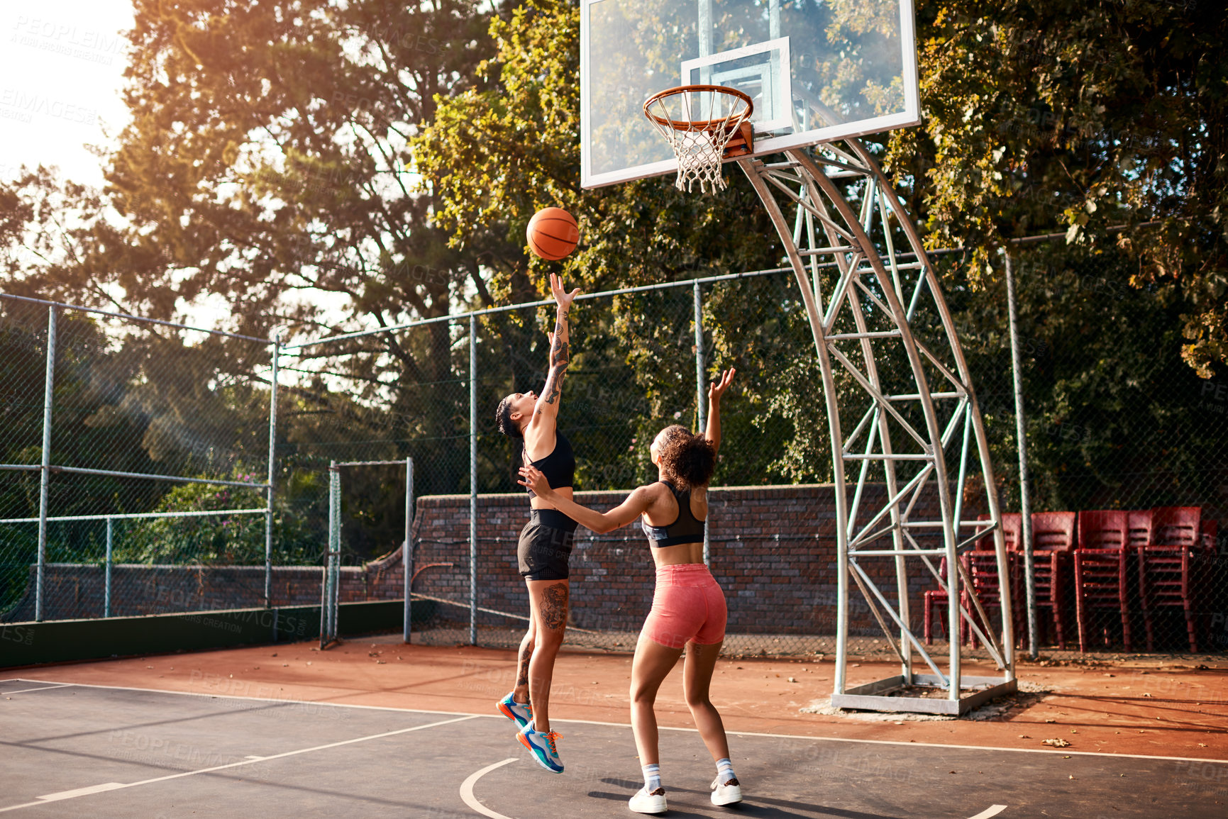 Buy stock photo Cropped shot of an attractive young sportswoman blocking her opponent during a basketball game during the day