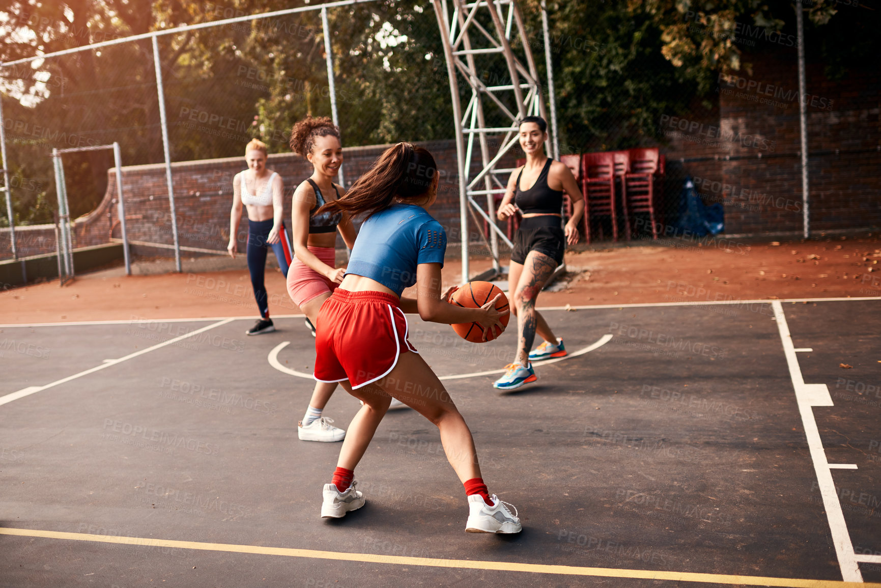 Buy stock photo Cropped shot of a diverse group of sportswomen playing a competitive game of basketball together during the day