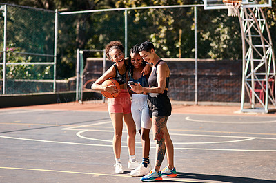 Buy stock photo Cropped shot of a diverse group of sportswomen standing together after playing basketball and looking at a cellphone