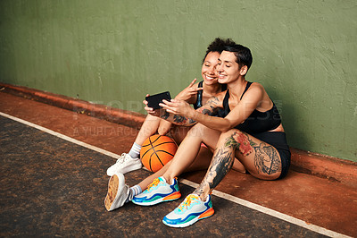Buy stock photo Cropped shot of two attractive sportswomen sitting together for a selfie after a basketball game during the day