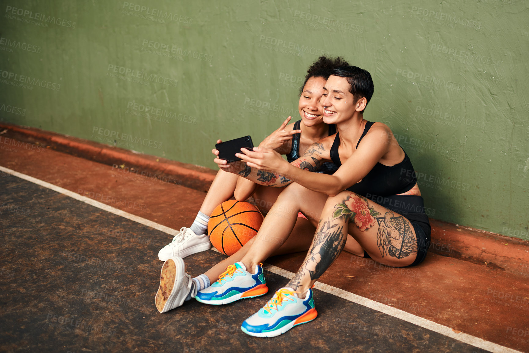 Buy stock photo Cropped shot of two attractive sportswomen sitting together for a selfie after a basketball game during the day
