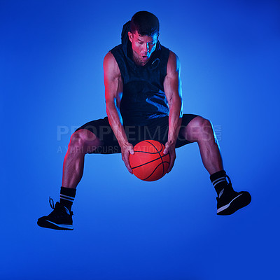 Buy stock photo Blue filtered shot of a sportsman playing basketball in the studio