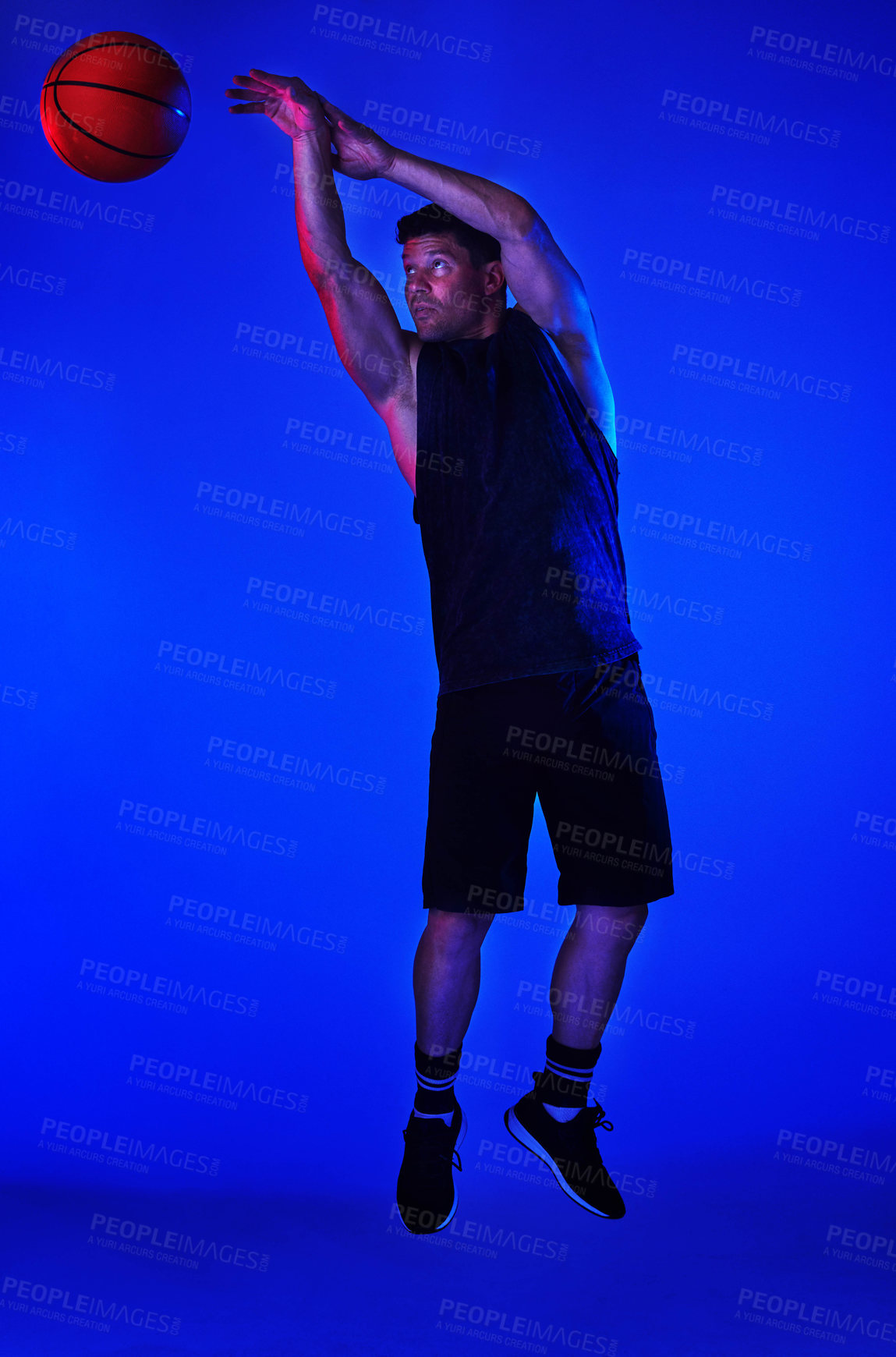 Buy stock photo Blue filtered shot of a sportsman playing basketball in the studio