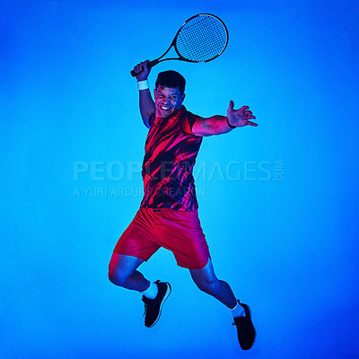 Buy stock photo Blue filtered shot of a man posing with a tennis racket in the studio