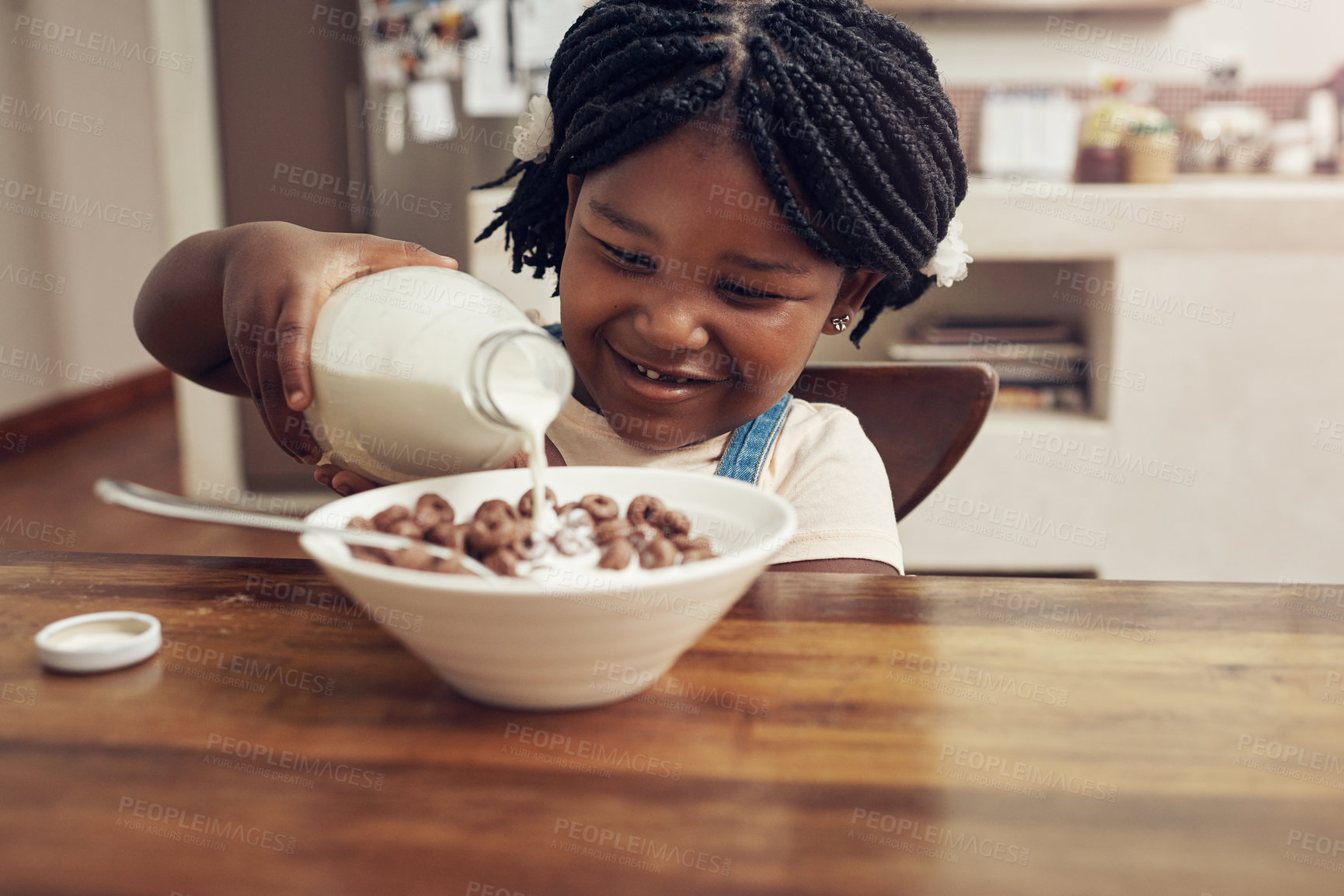 Buy stock photo Cropped shot of an adorable little girl pouring milk into her cereal bowl at home