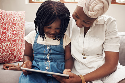 Buy stock photo Cropped shot of an adorable little girl using a digital tablet while bonding with her mother at home