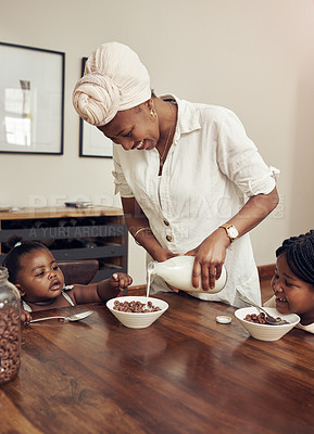 Buy stock photo Cropped shot of a young mother preparing cereal for her two adorable young daughters at home