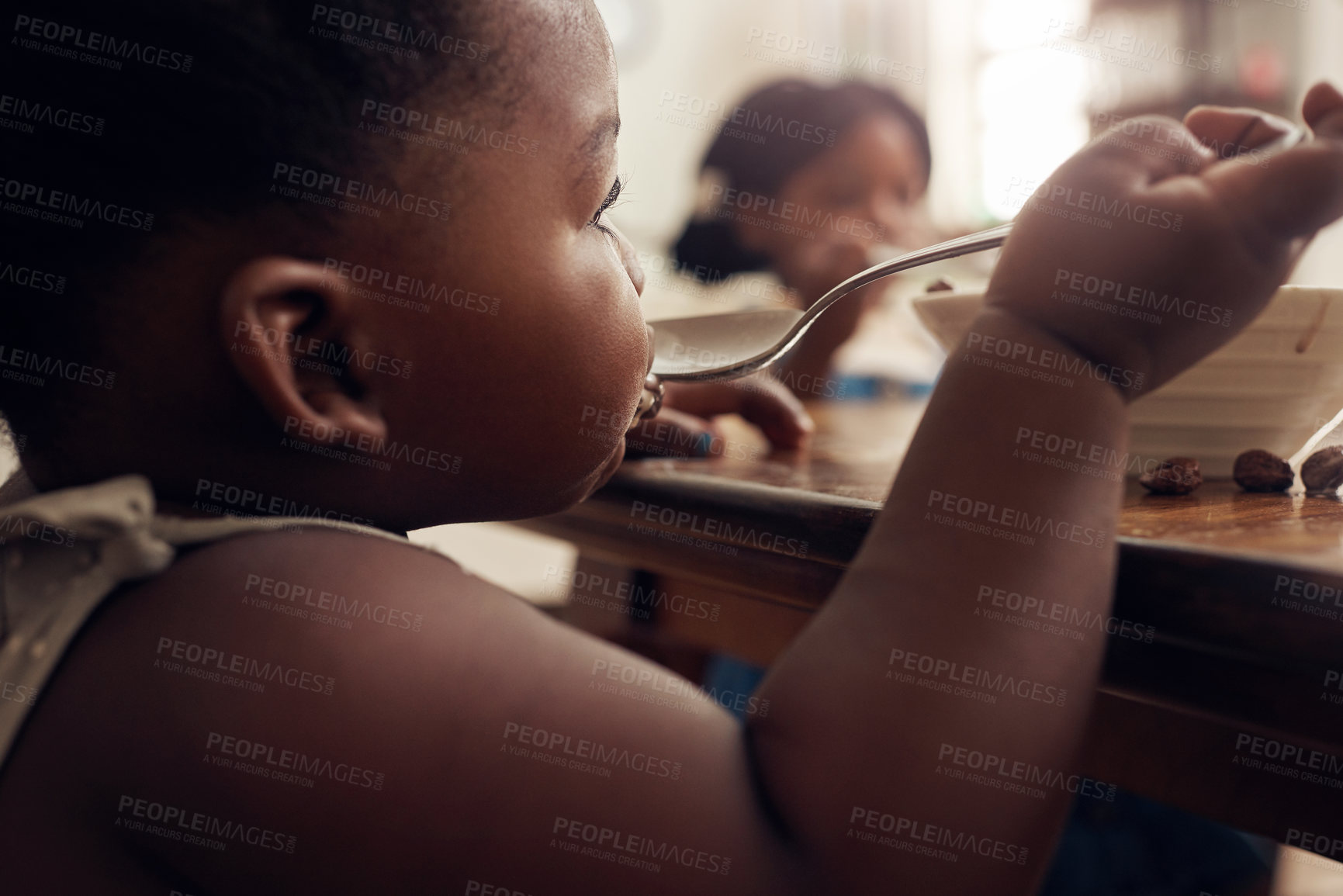 Buy stock photo Black child, cereal spoon and eating baby in a home kitchen with food and bowl at breakfast. African girl, nutrition and youth in a house with hungry kid relax with healthy snack and kids at morning