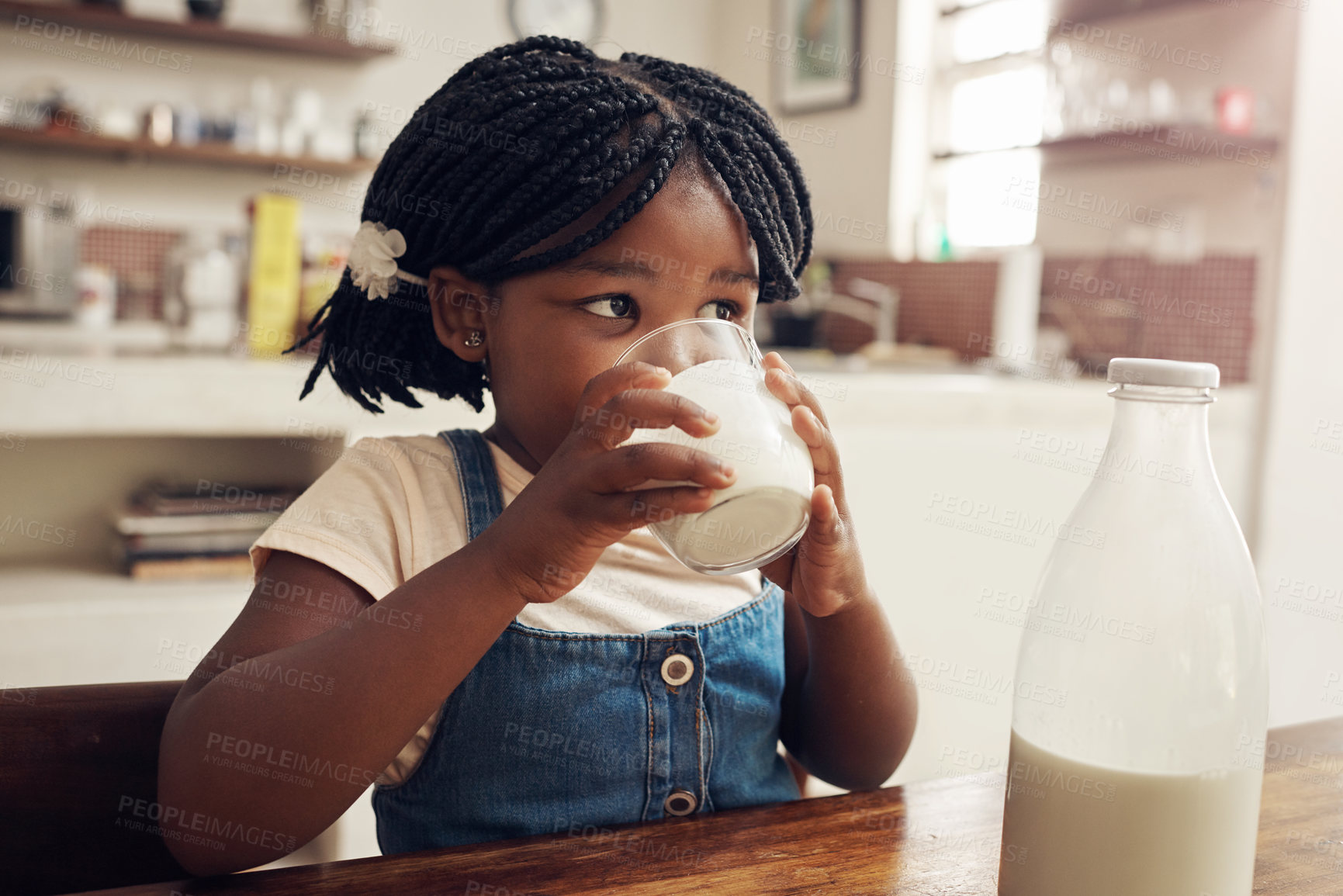 Buy stock photo Black child, drink and milk in home for nutrition, hygiene and dental health in kitchen table. Family house, girl and glass of dairy product for wellness, protein and vitamins for growth for kid