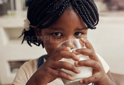 Buy stock photo Portrait of an adorable little girl drinking a glass of milk at home