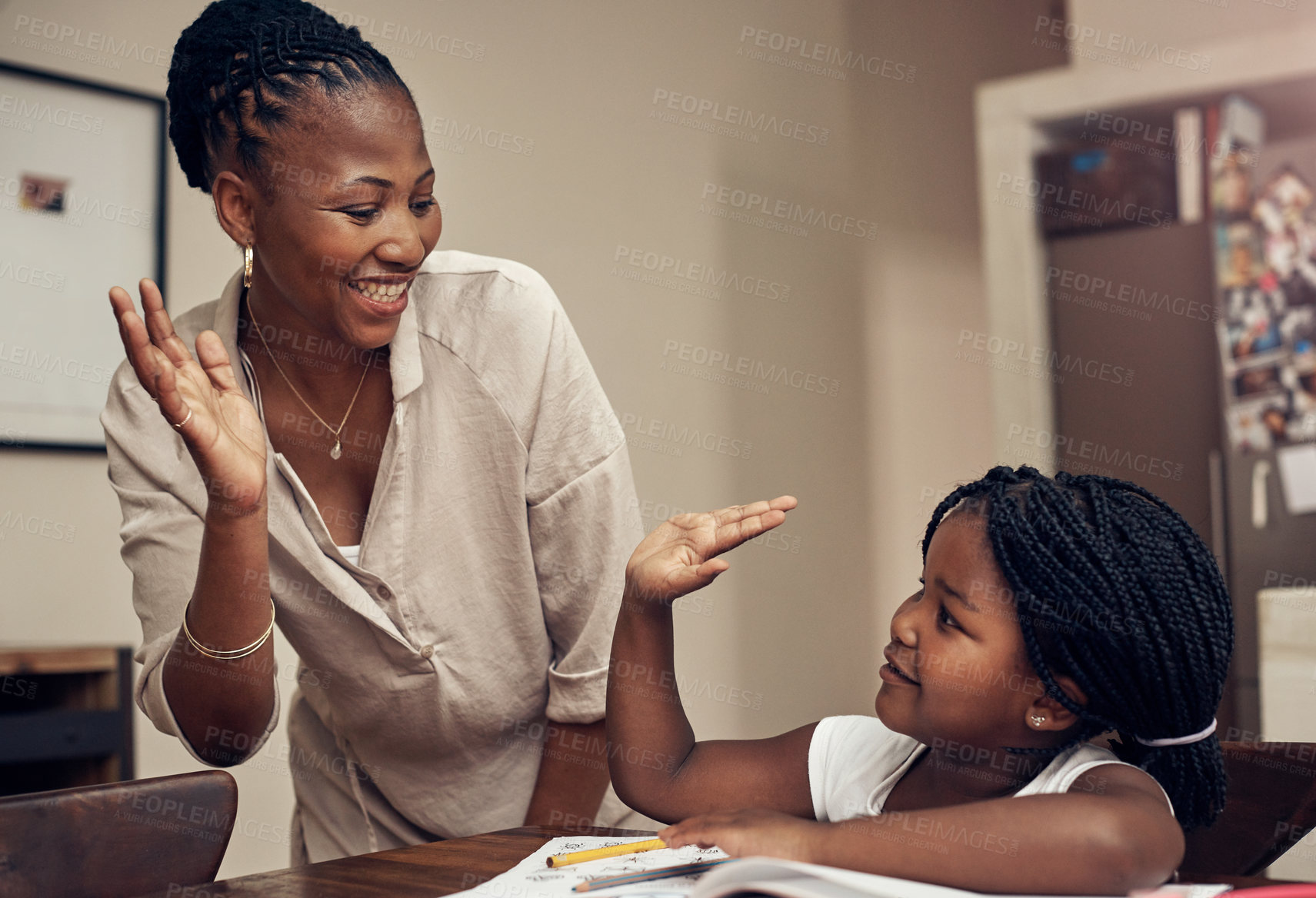 Buy stock photo Cropped shot of a young mother and daughter joining hands for a high five while doing homework together at home