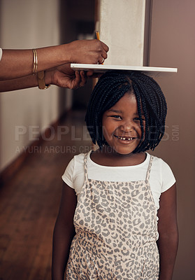 Buy stock photo Cropped shot of a mother measuring the height of her adorable young daughter at home