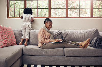 Buy stock photo Full length shot of a mother sitting on a couch and using her laptop while relaxing with her daughter at home
