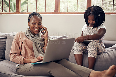 Buy stock photo Shot of a beautiful young mother making calls and using a laptop while relaxing with her young daughter at home