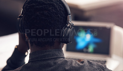 Buy stock photo Rearview shot of an unrecognizable businessman using a laptop while wearing headphones in a modern office