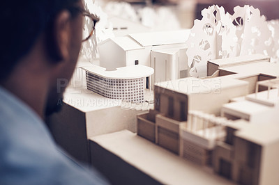 Buy stock photo Cropped shot of an unrecognizable male architect looking at a scale model while working in a modern office