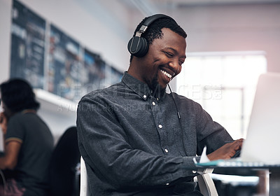 Buy stock photo Cropped shot of a handsome young businessman using a laptop while wearing headphones in a modern office