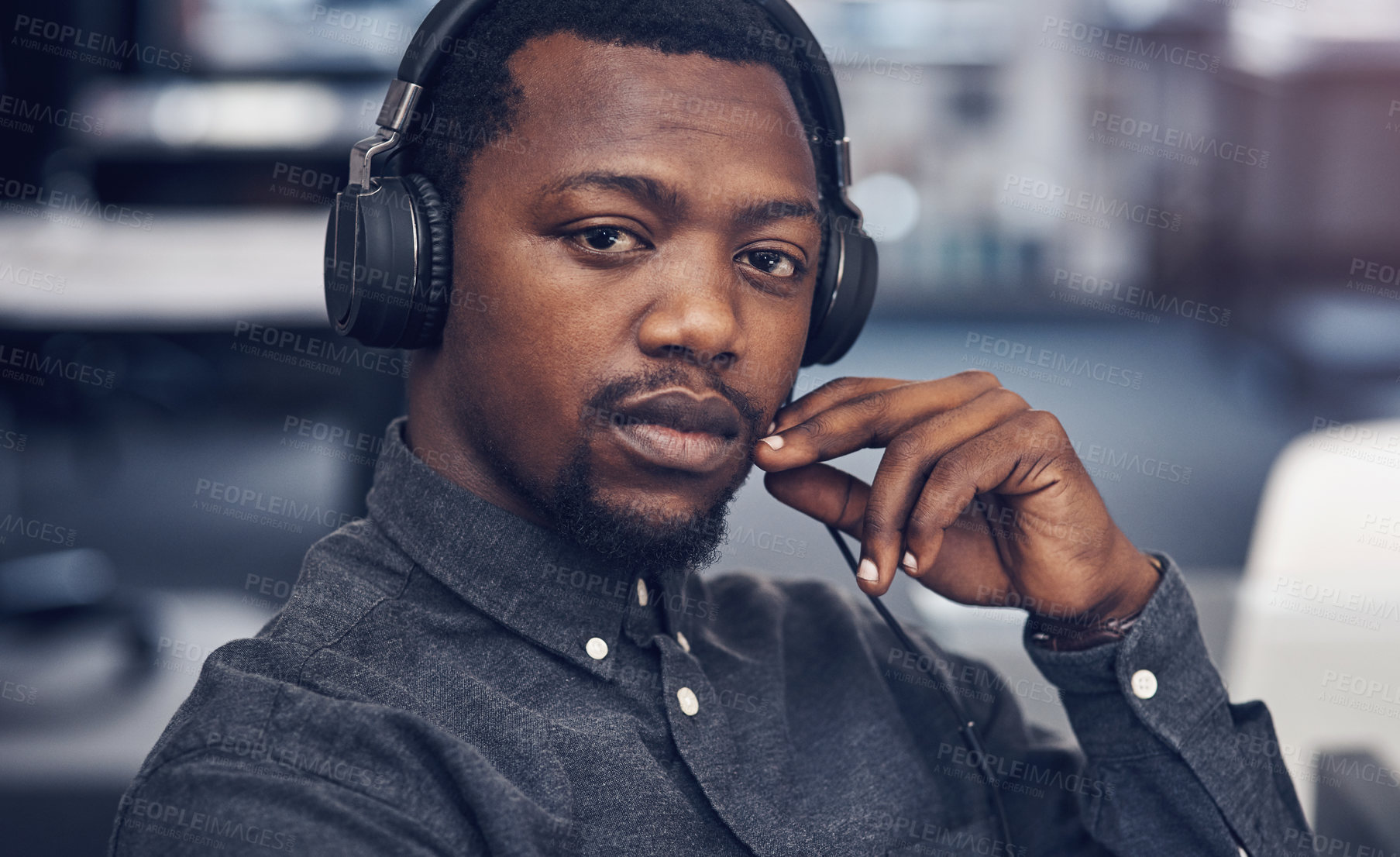 Buy stock photo Cropped portrait of a handsome young male architect wearing headphones while sitting in a modern office