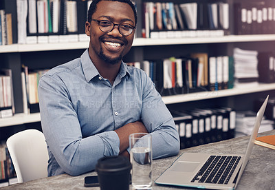 Buy stock photo Cropped portrait of a handsome young male architect smiling while working on a laptop in a modern office