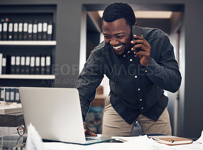 Buy stock photo Cropped shot of a handsome young male architect taking a phonecall while working on a laptop in a modern office