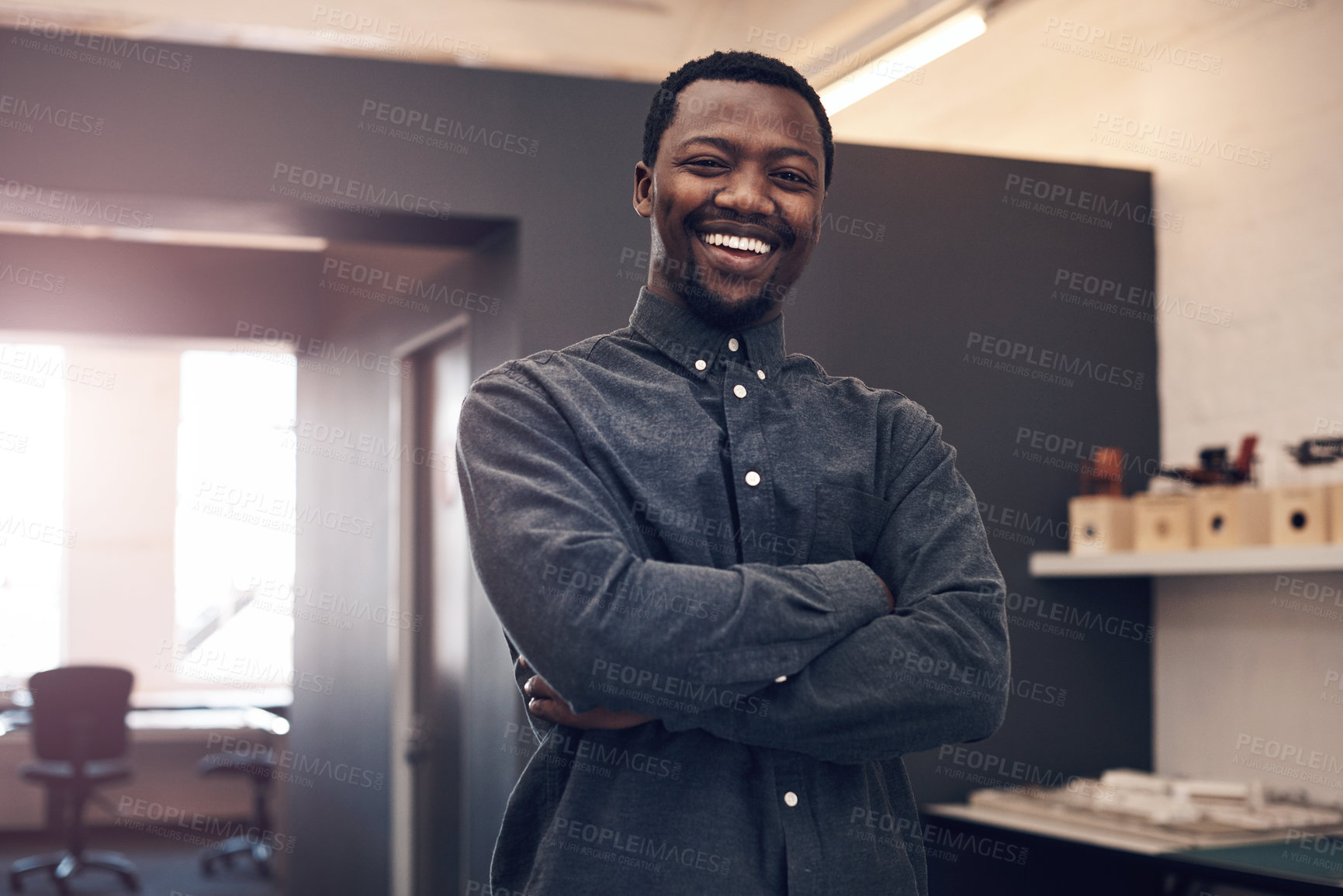 Buy stock photo Cropped portrait of a handsome young male architect smiling while standing with his arms crossed in a modern office