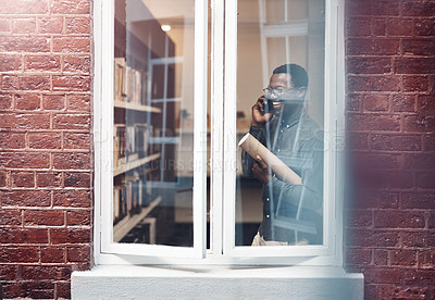 Buy stock photo Cropped shot of a handsome young male architect taking a phonecall while standing at his office window