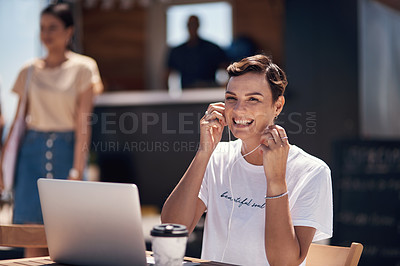 Buy stock photo Portrait of a cheerful young woman listening to music while working on her laptop next to a coffee truck outside during the day