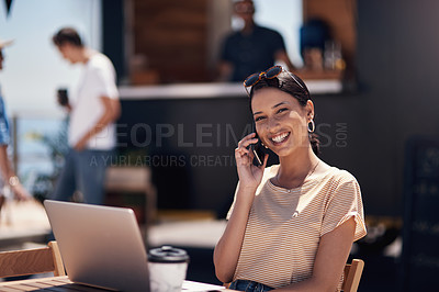 Buy stock photo Portrait of a cheerful young woman talking on her cellphone while doing work on her laptop next to a beach promenade outside during the day