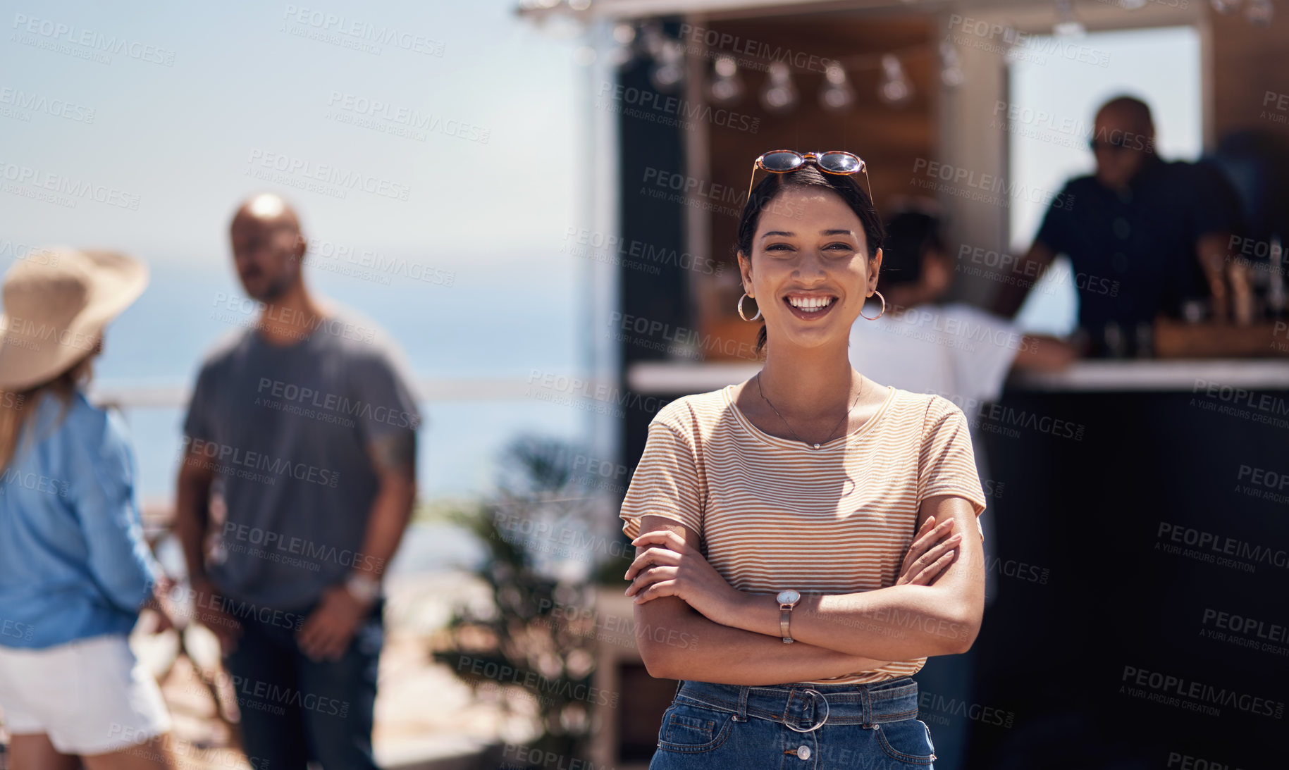 Buy stock photo Portrait of a cheerful young woman smiling brightly while standing outside on a beach promenade during the day