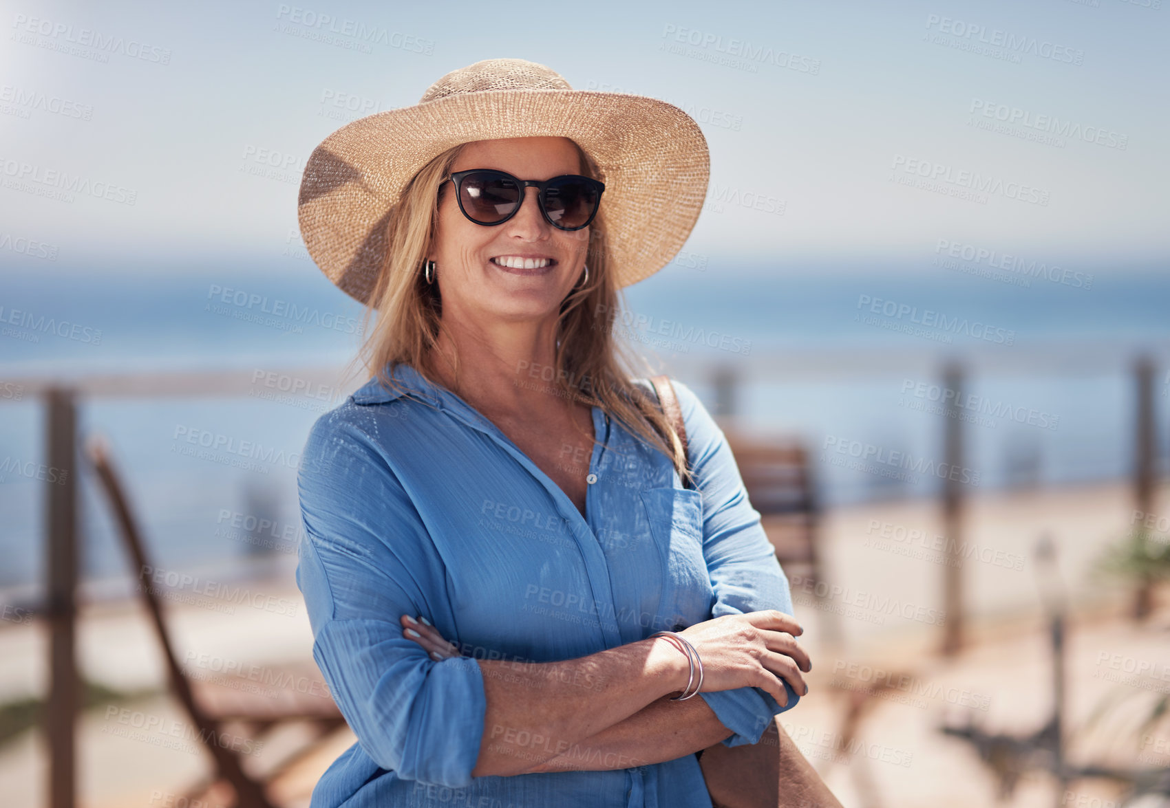 Buy stock photo Portrait of a cheerful middle aged woman smiling brightly while standing outside on a beach promenade during the day