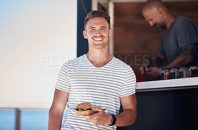 Buy stock photo Portrait of a cheerful young waiter holding a serving of food to give to a customer outside next to a coffee truck during the day