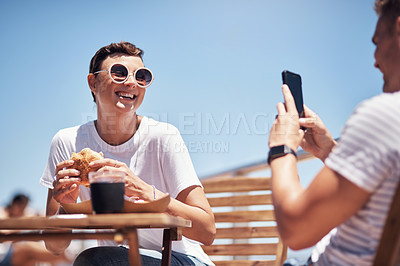 Buy stock photo Cropped shot of a cheerful young woman getting her picture taken by her boyfriend outside while they have lunch
