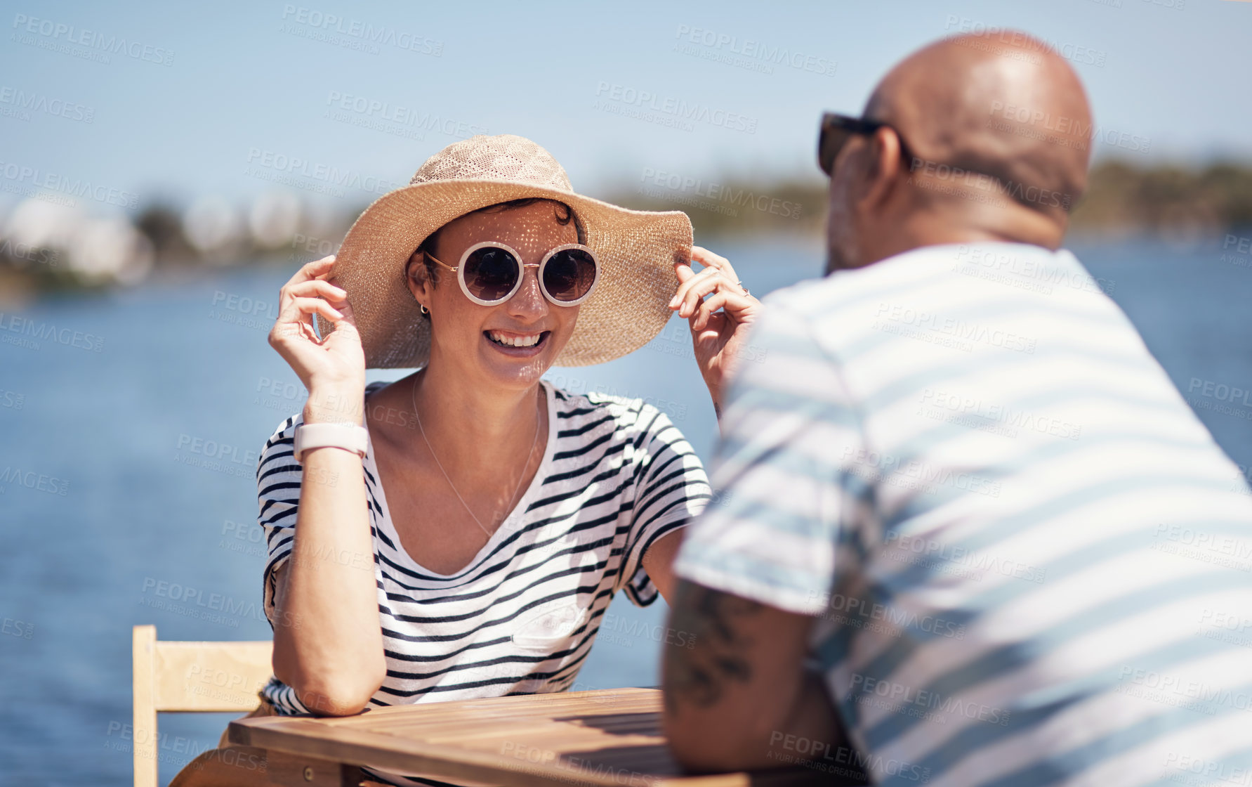 Buy stock photo Couple, smile and travel with happy conversation at harbor, vacation or date by waterfront in summer sunshine. Man, woman and listening with care, romantic bonding or love by sea for outdoor holiday