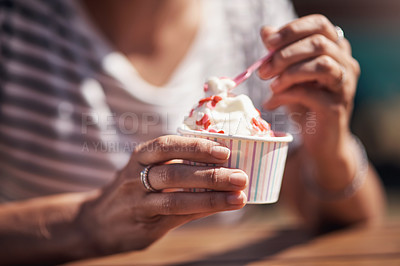 Buy stock photo Cropped shot of an unrecognisable woman having a helping of ice-cream while being seated at a table outside during the day