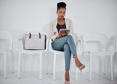Buy stock photo Shot of a young businesswoman using a digital tablet while sitting in a line against a white background