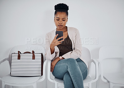 Buy stock photo Shot of a young businesswoman using a cellphone while sitting in a line against a white background