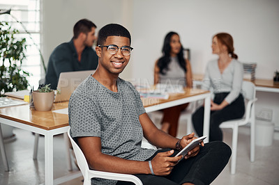 Buy stock photo Portrait of a young businessman using a digital tablet in an office with his colleagues in the background