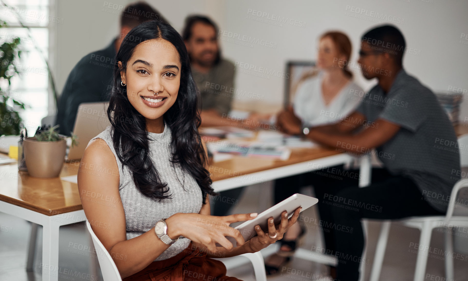 Buy stock photo Portrait of a young businesswoman using a digital tablet in an office with her colleagues in the background