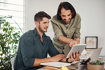 Buy stock photo Shot of two businessmen using a digital tablet together in an office