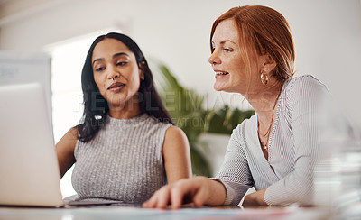 Buy stock photo Shot of two businesswomen working together on a laptop in an office