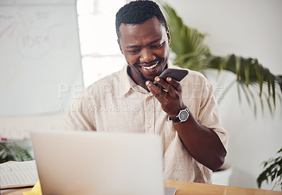 Buy stock photo Shot of a young businessman talking on a cellphone while using a laptop in an office