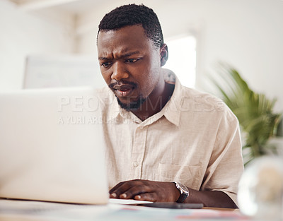 Buy stock photo Shot of a young businessman looking confused while using a laptop in an office