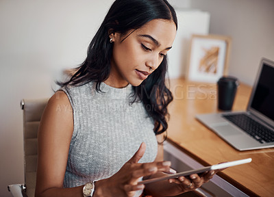 Buy stock photo Shot of a young businesswoman using a digital tablet in an office