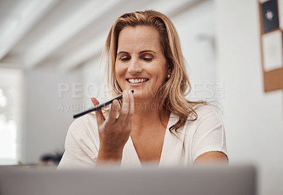 Buy stock photo Shot of a mature businesswoman talking on a cellphone while using a laptop in an office