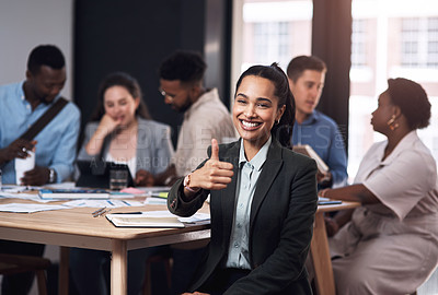 Buy stock photo Portrait of a young businesswoman showing thumbs up in an office with her colleagues in the background