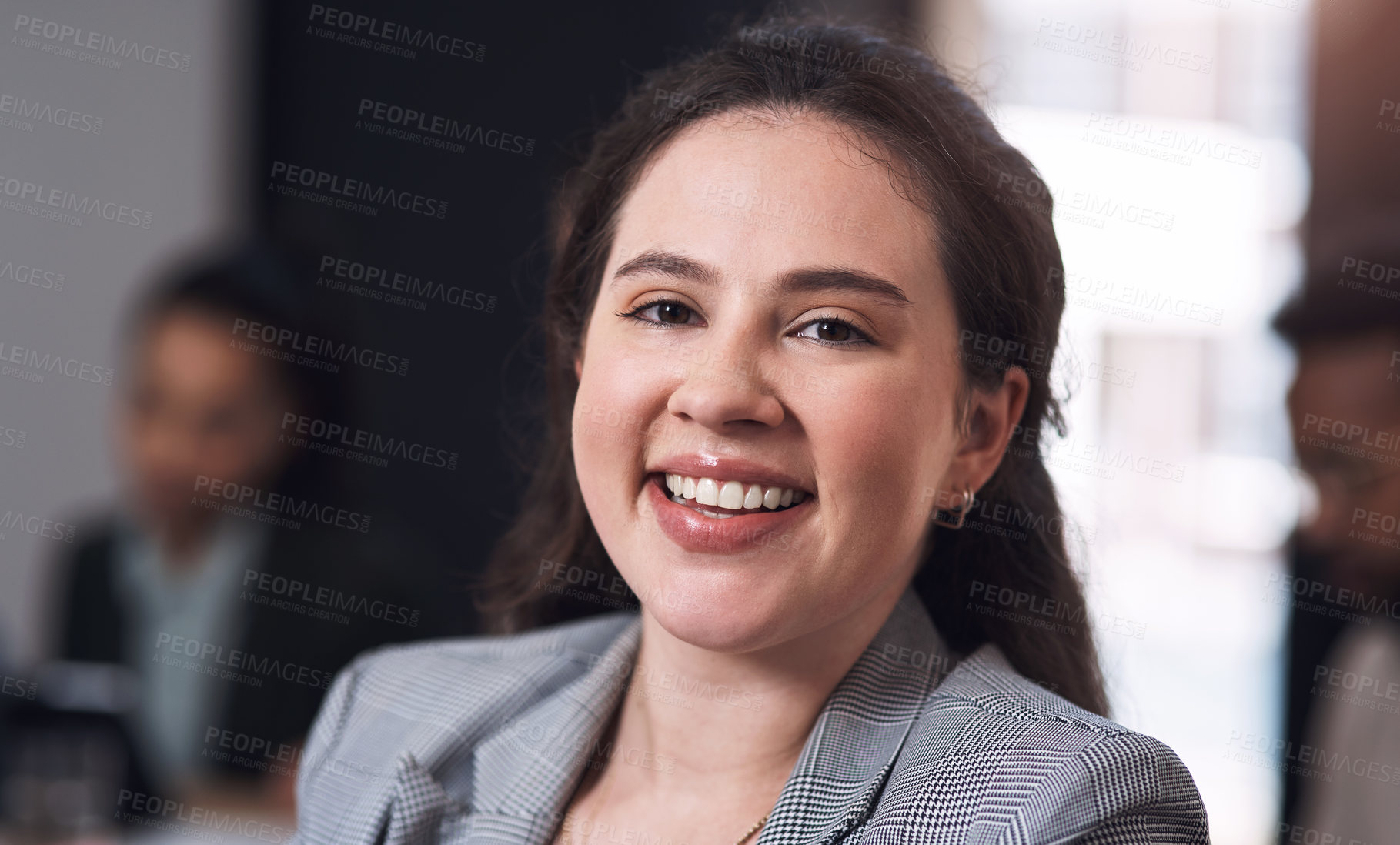 Buy stock photo Portrait of a young businesswoman sitting in an office with her colleagues in the background